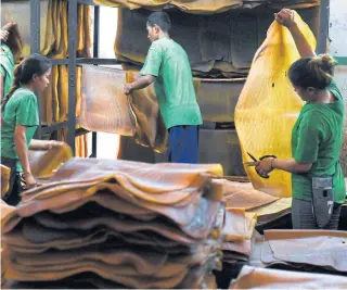  ?? AFP ?? Workers sort out raw rubber sheets at a factory in Rayong province. Rubber prices in Thailand have plunged significan­tly because of the US-China trade war.