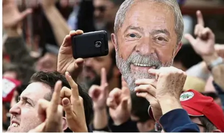  ?? AFP ?? Show of support: A Lula follower holding a mask bearing the former president’s likeness during a campaign rally outside the federal police headquarte­rs in Curitiba. —