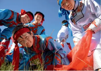  ??  ?? Mongolian children play on the grassland in summer.