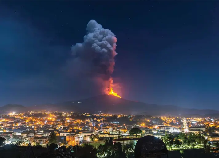  ??  ?? Flames and smoke billowing from a crater, as seen from the southern side of the Mt Etna volcano, tower over the city of Pedara, Sicily, Wednesday night. Europe's most active volcano has been steadily erupting since last week, belching smoke, ash, and fountains of red-hot lava. Photo: AP