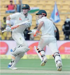  ??  ?? BANGALORE: Australian batsmen David Warner (R) and Matthew Renshaw run between the wickets during the first day of the second cricket Test match between India and Australia at The M. Chinnaswam­y Stadium in Bangalore yesterday. — AFP