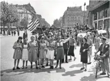  ?? AP PHOTO/HARRY HARRIS ?? French civilians with hastily made American and French flags greet U.S. and Free French troops entering Paris on Aug. 25, 1944 after Allied liberation of the French capital from Nazi occupation in World War II.