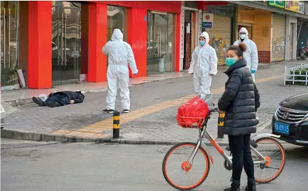 ?? —AFP ?? A man wearing a face mask lies dead on the pavement at ground zero of China’s virus epidemic, a plastic shopping bag in one hand.