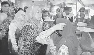  ??  ?? UTAMA KEBERSIHAN: Jamilah memakaikan apron kepada seorang peniaga di Bazar Ramadan MBKS semalam.