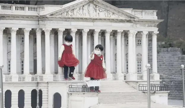  ??  ?? 0 As China eases lockdown restirctio­ns, children stand on the steps of a scaled replica of the United States Capitol Building at Beijing’s World Park