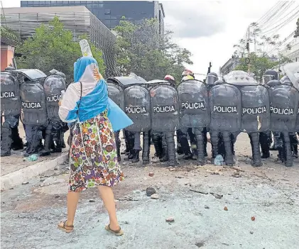  ??  ?? bandera. Una mujer, en la tierra de Gildo Insfrán, delante de un batallón de policías y sus escudos.