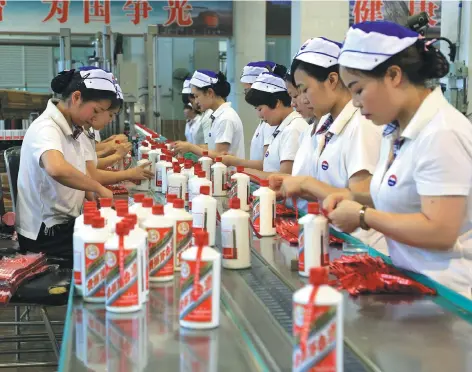  ?? PHOTO BY YANG JUN / CHINA DAILY ?? Workers fix labels to bottles of Kweichow Moutai, a famous Chinese liquor, at the company’s production line. The company will visit Cape Town for a major brand promotion event.