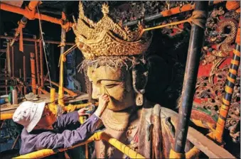  ?? HU DATIAN / FOR CHINA DAILY ?? Li Yunhe, 86, an expert in the repair of cultural relics, fixes a Ming Dynasty (1368-1644) Buddha statue at a temple in Xinjin county of Chengdu, Sichuan province, on Wednesday. The repair work is expected to conclude soon.