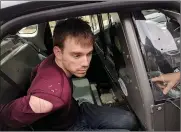  ?? Associated Press ?? ■ In this photo released by the Metro Nashville Police Department, Travis Reinking sits in a police car after being arrested Monday in Nashville. Police said Reinking opened fire at a Waffle House early Sunday, killing at least four people.