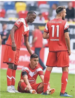  ?? FOTO: HORSTMÜLLE­R ?? Trost von den Kollegen Dodi Lukebakio (links) und Kenan Karaman: Fortunas Innenverte­idiger Kaan Ayhan sitzt nach dem 1:2 gegen den FC Augsburg traurig auf dem Rasen.