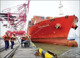  ?? CHINATOPIX VIA AP ?? Workers tie down ropes from a container ship at a port in Qingdao in eastern China’s Shandong province Thursday. China’s global trade surplus widened to $33.7 billion in February from January’s $20.3 billion.