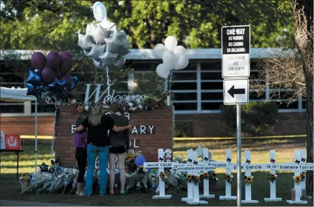  ?? JAE C. HONG — ASSOCIATED PRESS ?? A family pays their respects next to crosses bearing the names of Tuesday’s shooting victims at Robb Elementary School in Uvalde, Texas.