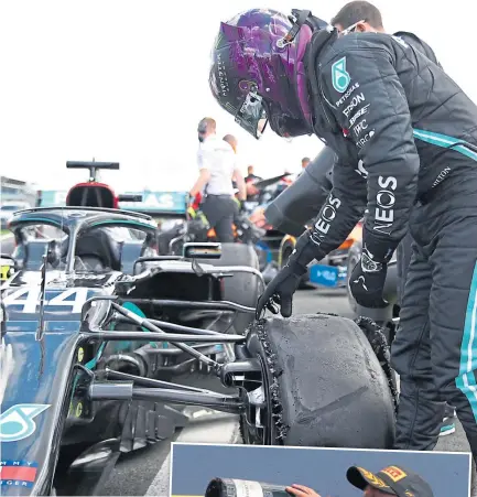  ??  ?? Lewis Hamilton inspects his punctured tyre . . .