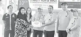  ??  ?? Azhar (third right) presenting the donation to a representa­tive of one of the charity homes during the AIDS Charity Run &amp; Walk 2018.