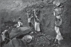  ?? The Associated Press ?? SCAVENGERS: People carry baskets of coal scavenged illegally Jan. 7 at an open-cast mine in the village of Bokapahari in the eastern Indian state of Jharkhand where a community of coal scavengers live and work.