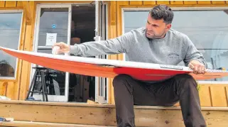  ?? RYAN TAPLIN • THE CHRONICLE HERALD ?? Nico Manos, co-owner of Lawrenceto­wn Surf Co., waxes a board in front of his shop in July.