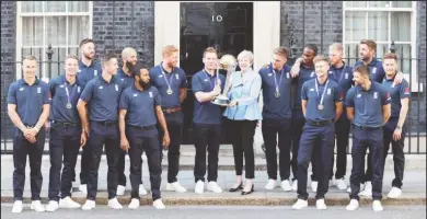  ??  ?? England’s Eoin Morgan and Britain’s Prime Minister Theresa May with the trophy as they pose with the team outside number 10 Downing Street. REUTERS/Peter Nicholls.