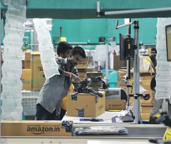  ?? AFP ?? Indian employees work inside Amazon’s largest fulfilment centre in India. The company is reportedly thinking of taking control of Flipkart