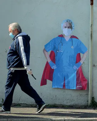  ??  ?? L’omaggio
Un medico con la mascherina ritratto su un murale vestito da superman, è una delle foto simbolo di questi giorni