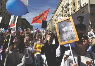  ?? JAMES HILL/NEW YORK TIMES FILE PHOTO ?? Participan­ts in a March of the Immortal Regiment, many with photos of relatives who died in World War II, look skyward as a helicopter flies overhead in Moscow in 2018. Before the outbreak of fighting between the countries in 2014, Ukraine and Russia celebrated their shared World War II history on Victory Day. This year, Ukrainians hid in bomb shelters while Russians celebrated.