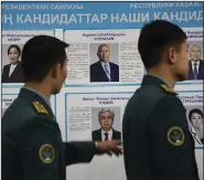  ?? (AP/NUR.KZ/Vladimir Tretyakov) ?? Kazakh servicemen line up to cast their votes next to a poster showing presidenti­al candidates Sunday at a polling station in Almaty, Kazakhstan.