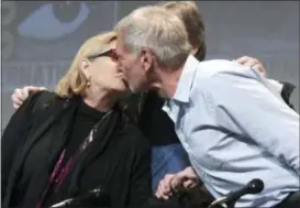  ?? PHOTO BY RICHARD SHOTWELL — INVISION — AP, FILE ?? In this file photo, Carrie Fisher, left, and Harrison Ford kiss at the Lucasfilm’s “Star Wars: The Force Awakens” panel on day 2 of Comic-Con Internatio­nal in San Diego. Fisher, a daughter of Hollywood royalty who gained pop-culture fame as Princess...