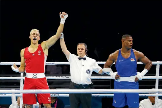  ?? PHOTO: PHOTOSPORT ?? New Zealand’s David Nyika, left, gets the decision in his favour against England’s Cheavon Clarke, putting the Kiwi into the gold medal fight today.