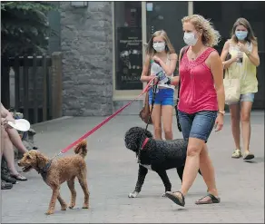  ??  ?? Visitors wear surgical masks to protect themselves from smoke in Whistler on Tuesday. There are 184 fires burning across the province.