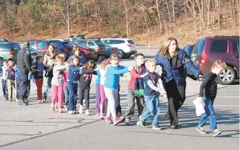  ?? SHANNON HICKS/NEWTOWN BEE/MCT ?? State police personnel lead children from the Sandy Hook Elementary School after the Dec. 14, 2012, mass shooting there. Tamaqua Area first considered arming teachers in wake of that massacre.