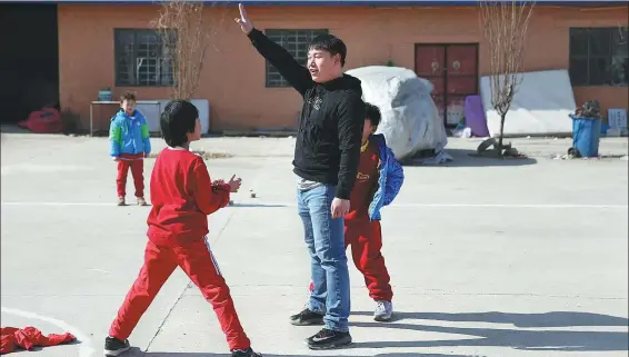  ?? PHOTOS BY ZOU HONG / CHINA DAILY ?? Shao Pengchao (in black), a staff member at Sun Village, an NGO offering free aid to the children of inmates, guides young children playing games in Beijing’s Shunyi district.