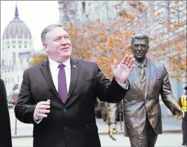  ?? Attila Kisbendek The Associated Press ?? Secretary of State Mike Pompeo stands Monday next to a scuplture of former President Ronald Reagan in Budapest, Hungary.