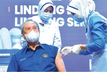 ?? - Bernama photo ?? Muhyiddin receiving the first Pfizer-BioNTech Covid-19 vaccine in Malaysia to kickstart the National Covid-19 Immunisati­on Programme at the Putrajaya Health Office in Precinct 11, yesterday.