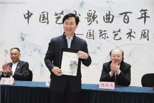  ??  ?? Liao Changyong, president of the Shanghai Conservato­ry of Music, displays “Three Wishes from a Rose — 16 Chinese Art Songs” at a ceremony in Shanghai marking the release of the German- published collection. — Ti Gong