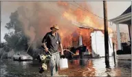  ??  ?? FIRE ON THE WATER: A man makes his way out of floodwater­s as a home burns in New Orleans on August 6, 2005 after Hurricane Katrina.