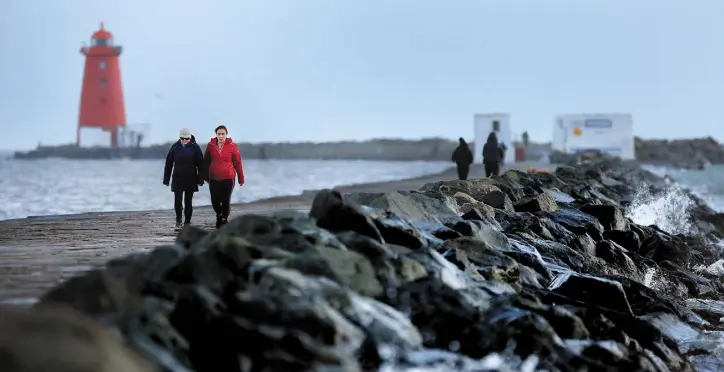  ?? Photo: Gerry Mooney ?? BEFORE THE STORM: Walkers on the Great South Wall in Dublin ahead of the arrival of Storm Dylan.