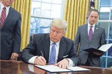  ?? AP PHOTO/EVAN VUCCI ?? President Donald Trump signs an executive order in the Oval Office to withdraw the U.S. from the 12-nation Trans-Pacific Partnershi­p trade pact agreed to under the Obama administra­tion.