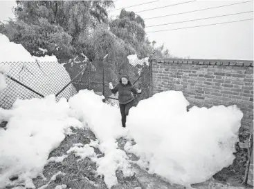  ?? JUAN BARRETO/GETTY-AFP ?? Avalanche of pollution: A woman walks through snow-like foam Tuesday in a neighborho­od west of Bogota, Colombia. The pungent foam formed in the polluted Mosquera River and invaded the Los Puentes neighborho­od. The foam is the result of industrial waste and untreated sewage.