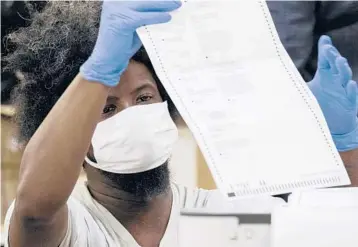  ?? BEN GRAY/AP 2020 ?? A worker scans a ballot from Fulton County, Georgia, during a recount Nov. 25 in Atlanta. Then-President Donald Trump lost Georgia, a Republican stronghold, to Democrat Joe Biden by about 12,000 votes in last year’s election.