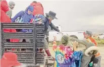  ?? Stringr via AP ?? Burning Man festivalgo­ers are helped off of a truck that left the Black Rock, Nev., site on Monday. An unusual late-summer storm stranded thousands at the weeklong event.