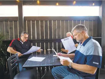  ?? RICK KINTZEL/THE MORNING CALL ?? Barry Heil, of Catasauqua, left, Tim Turner and Joe Adamchick, both of Pittsburgh, look over their menus Thursday on the new deck at Braveheart Highland Pub in Hellertown. The pub added the $45,000 deck to maximize its outdoor dining and has taken out other loans to stay afloat during the pandemic.