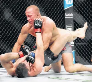  ?? AP PHOTO ?? Georges St-Pierre fights England’s Michael Bisping, below, during a middleweig­ht title mixed martial arts bout at UFC 217 on Sunday in New York.