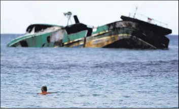  ?? Caleb Jones The Associated Press ?? A swimmer looks Wednesday at the Pacific Paradise, a commercial fishing vessel that ran aground about a month ago off Kaimana Beach in Honolulu.