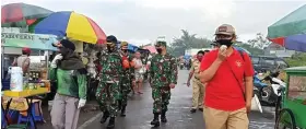  ?? GALIH ADI/JAWA POS ?? RUTIN SETIAP HARI: M. Djamil (kanan) bersama tiga pilar mengingatk­an pedagang dan pembeli untuk taat protokol kesehatan di Pasar OERR kemarin.