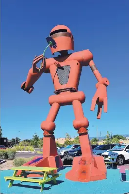  ?? MARTY FRENTZEL/JOURNAL ?? The giant robot in front of Meow Wolf, which operates the popular House of Eternal Return, finds the time to smell the roses in Santa Fe.