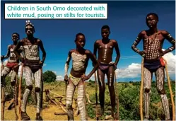  ??  ?? Children in South Omo decorated with white mud, posing on stilts for tourists.