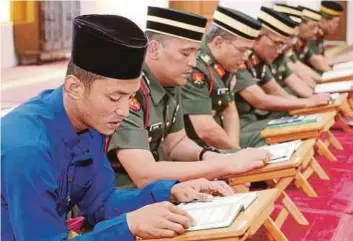  ??  ?? MOHD Asrul (kiri) bersama pegawai ATM 1 RAMD membaca yasin dan tahlil sempena Hari memperinga­ti Peristiwa Bukit Chandu di Surau As-Syafie.