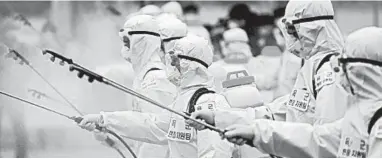  ?? YONHAP ?? Soldiers in protective gear spray disinfecta­nt as part of preventive measures against COVID-19 in Daegu, South Korea.