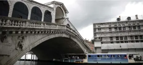  ?? MARCO BERTORELLO/AFP/GETTY IMAGES ?? A ferry passes under the Rialto bridge of the Grand Canal in Venice. The city’s ferry system puts Toronto’s island ferry to shame, Shawn Micallef writes.