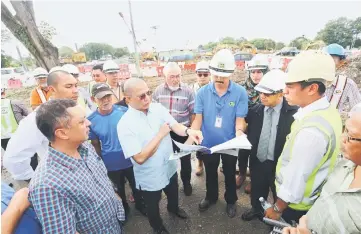  ??  ?? Fadillah (fourth left) and others listen to a briefing on the Datuk Temenggong Abang Kipali Abang Akip roundabout project by Tang (fourth right). — Photo by Mohd Rais Sanusi