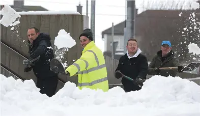  ??  ?? Locals Nigel Staveley, Stephen Corcoran and Darren Devereux were among the volunteers helping to clear snow from outside the Holy Family National School in Rathcoole, Co Dublin. Photo: Damien Eagers.